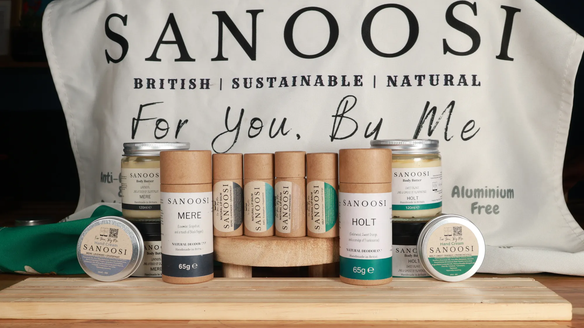 The SANOOSI range of deodorants, body butters and hand creams in front of a For You, By Me tote bag